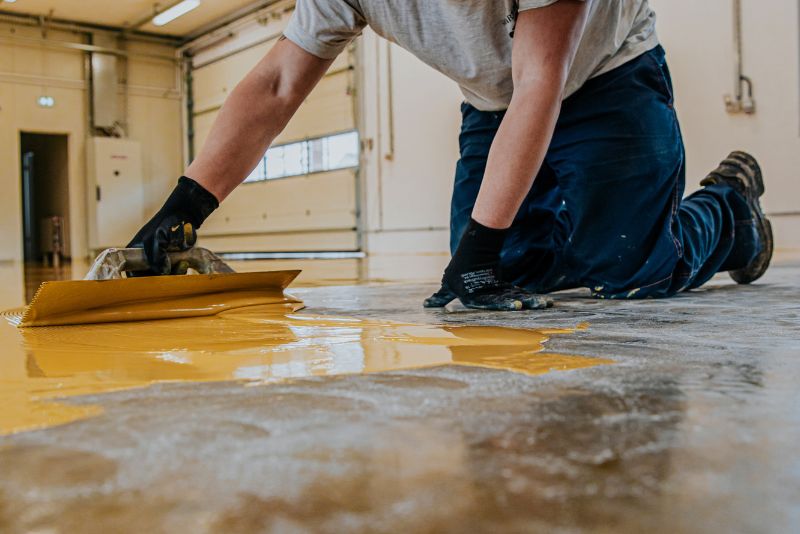 man applying epoxy mixture over concrete floor