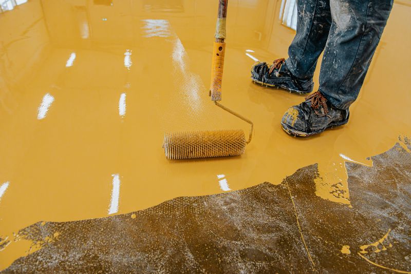 worker applying a coat of epoxy coating on the floor